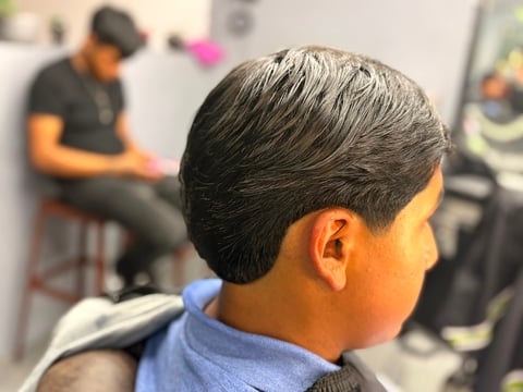 Close-up view of a person's head from behind showing a neatly groomed dark hairstyle with fade, indoors
